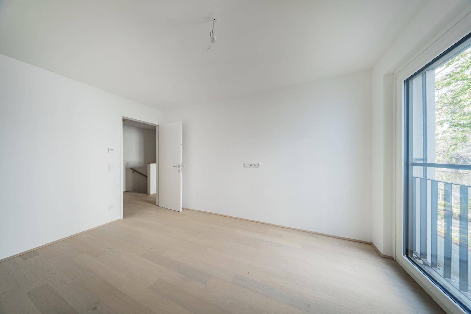 Helles Schlafzimmer mit Holzboden und französischem Balkon.
