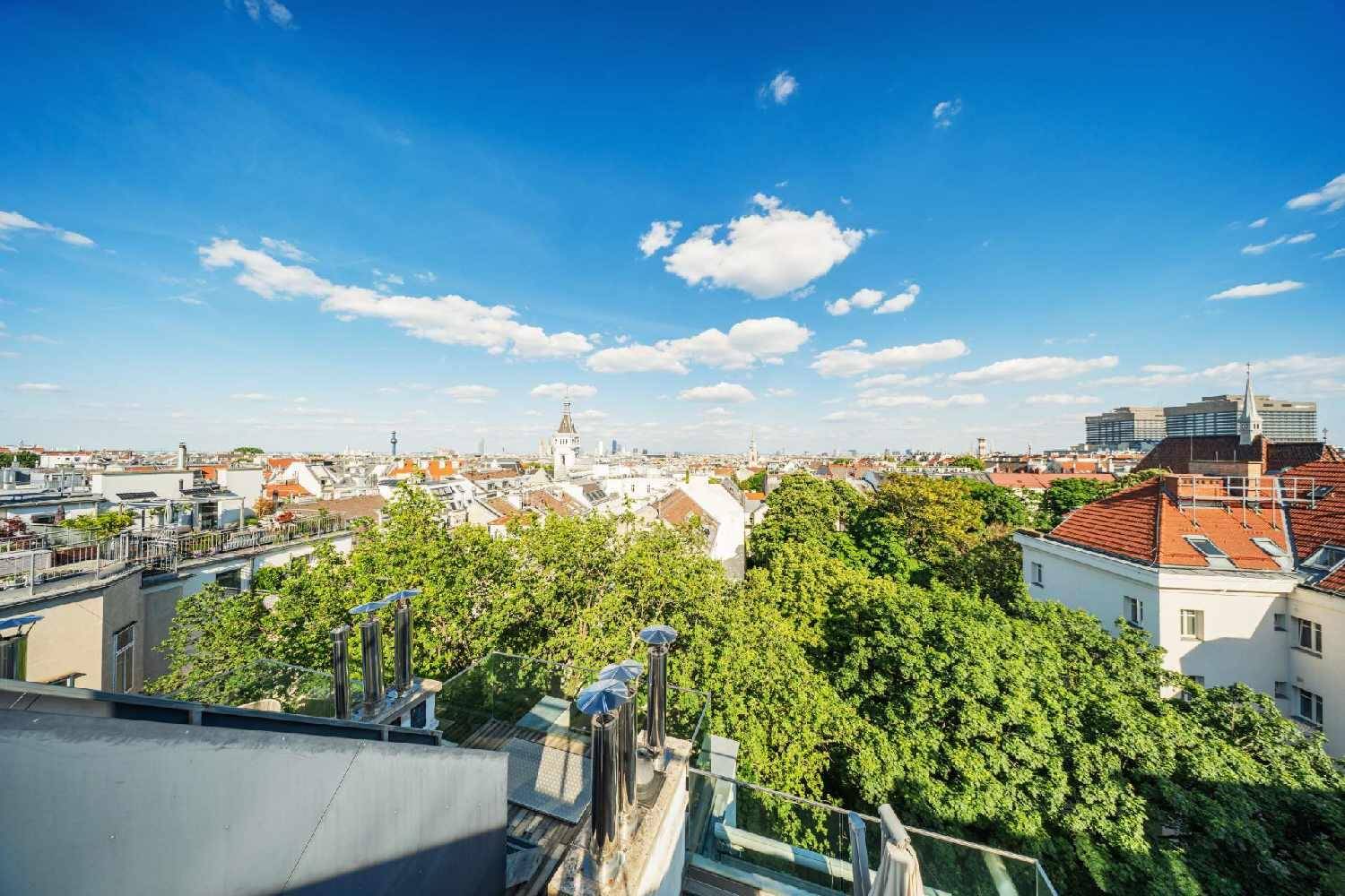 Panoramablick über die Dächer der Stadt mit viel Grün und blauem Himmel.