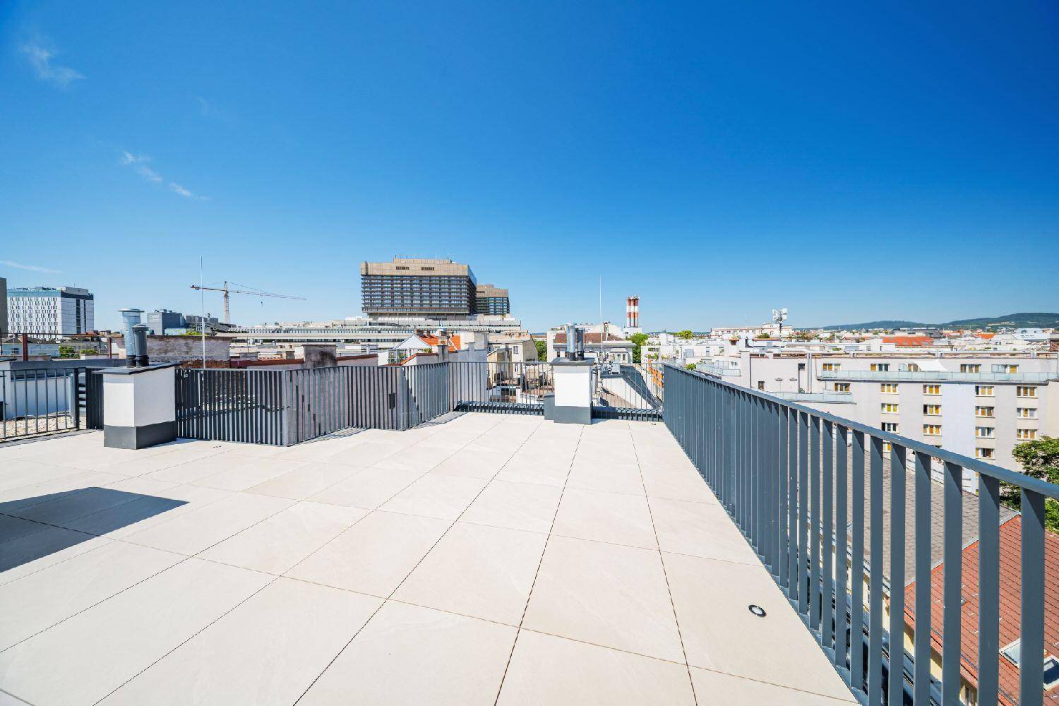 Weitläufige Dachterrasse mit Fliesenboden und beeindruckendem Panoramablick über die Stadt.