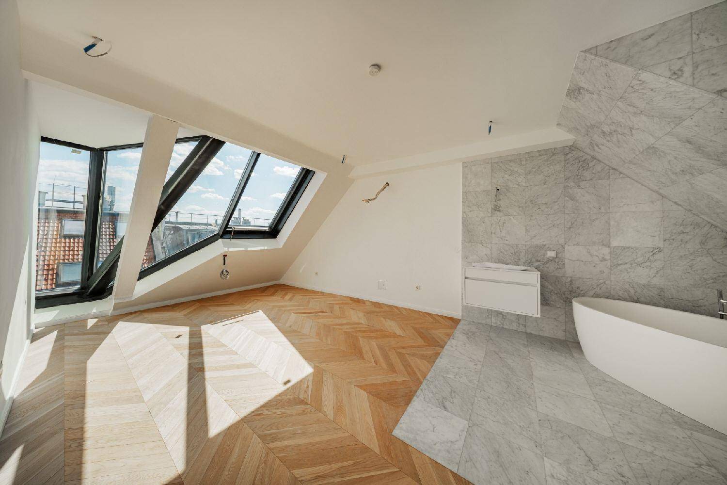 Modernes Badezimmer mit freistehender Badewanne, Marmorfliesen und großen Dachfenstern.