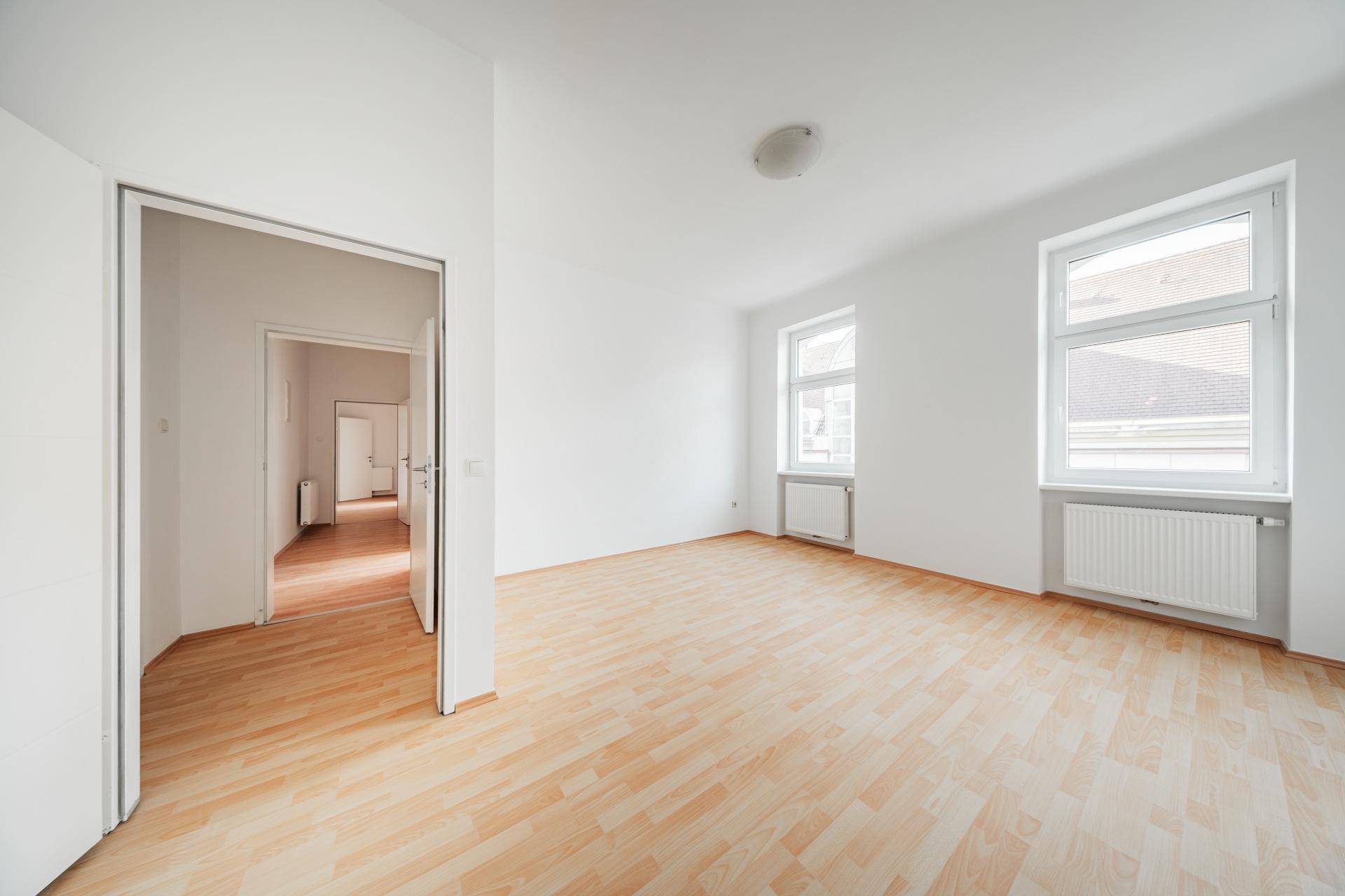 Heller Raum mit Laminatboden und Zugang zu weiteren Zimmern, ideal für flexible Nutzung.