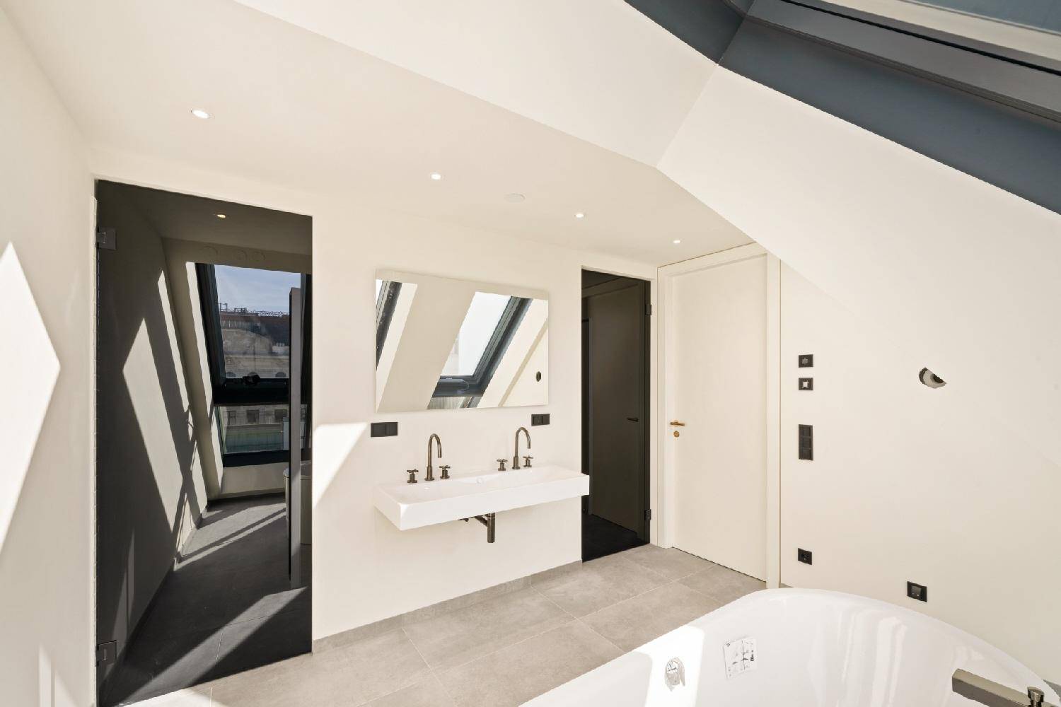 Elegantes Badezimmer mit Doppelwaschbecken, Spiegelschrank und schrägen Wänden unter Dachfenstern.