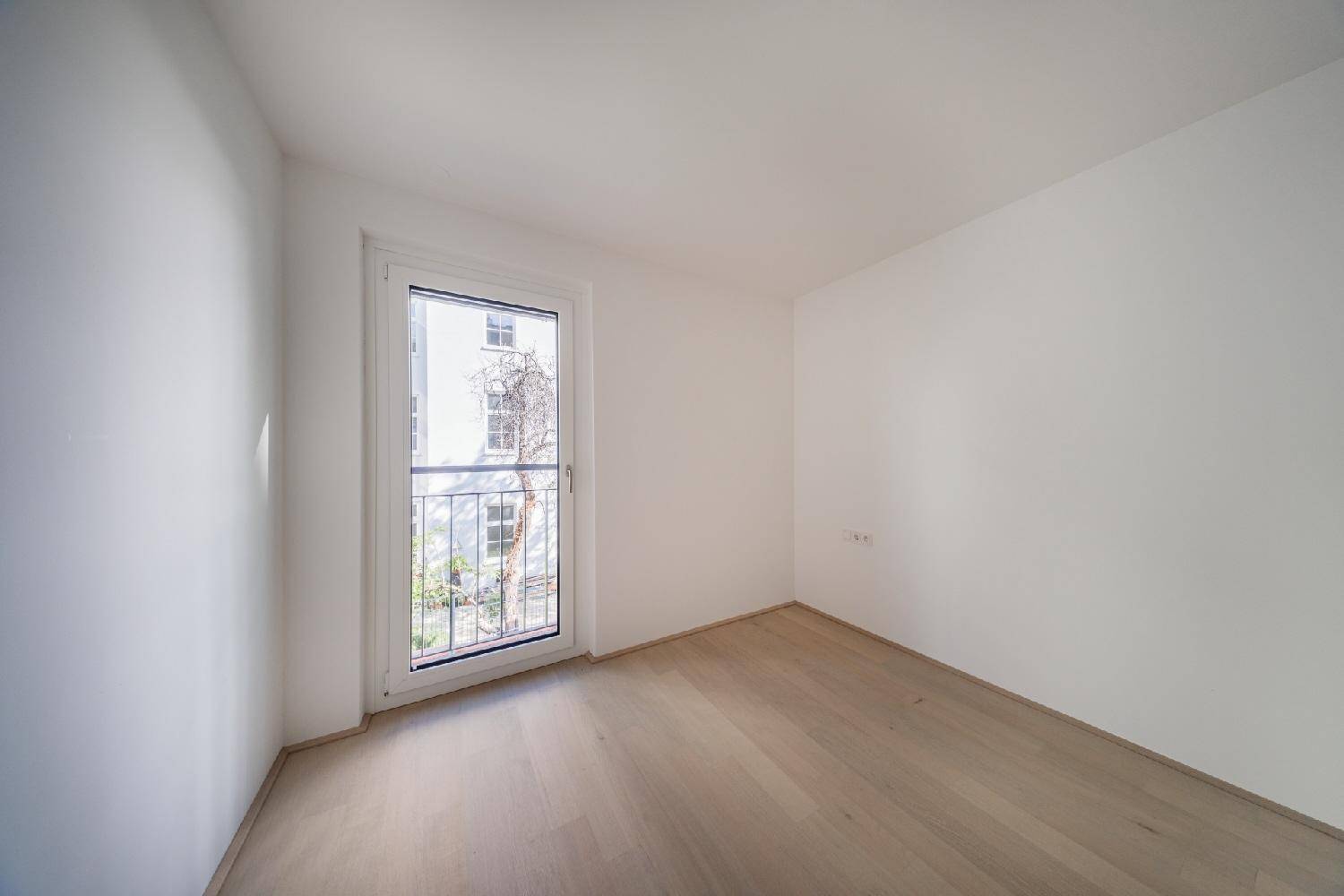 Kleines, helles Zimmer mit Holzboden und einem französischen Balkon, ideal als Schlaf- oder Arbeitszimmer.