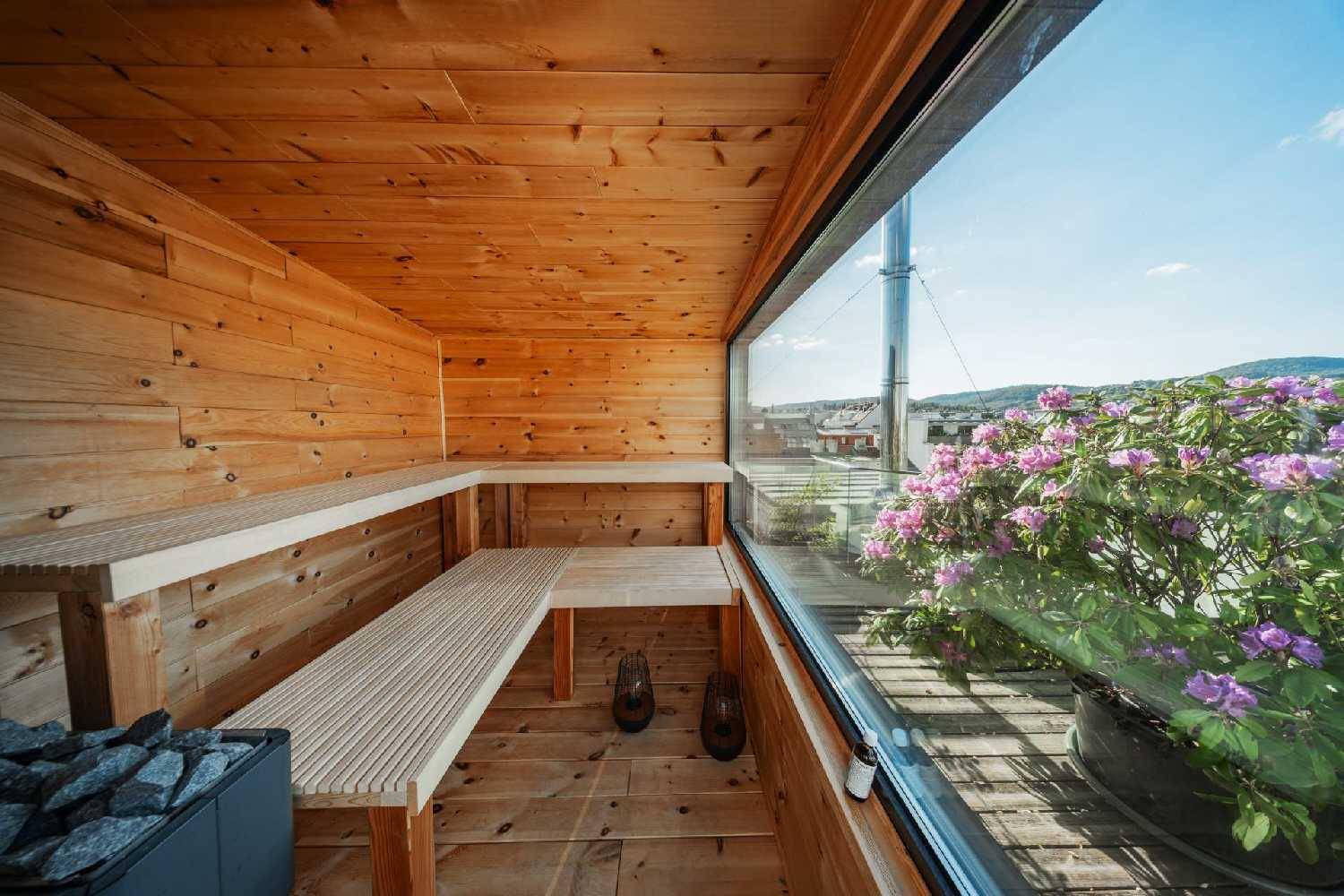 Gemütliche Holzsauna mit großer Fensterfront und Blick ins Grüne.