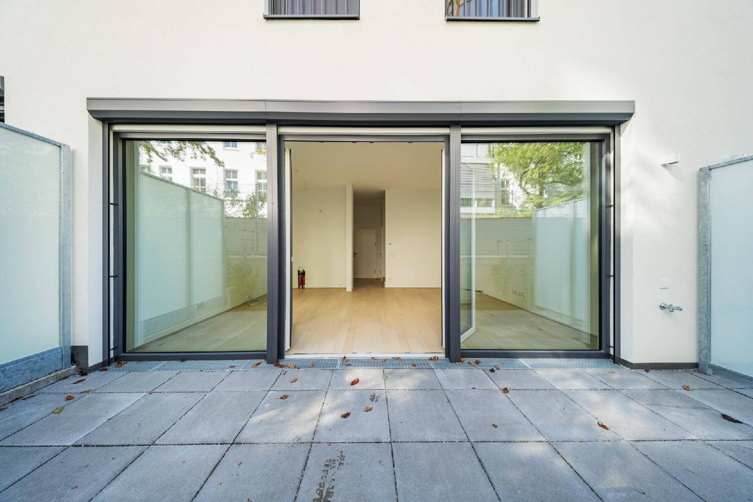 Geräumige Terrasse mit Steinplatten und direktem Zugang zum hellen Innenraum.
