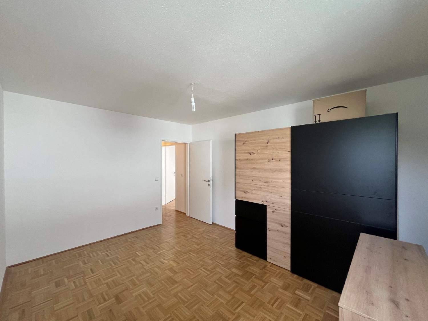 Geräumiges Schlafzimmer mit Parkettboden, weiß gestrichenen Wänden und einem modernen Kleiderschrank.
