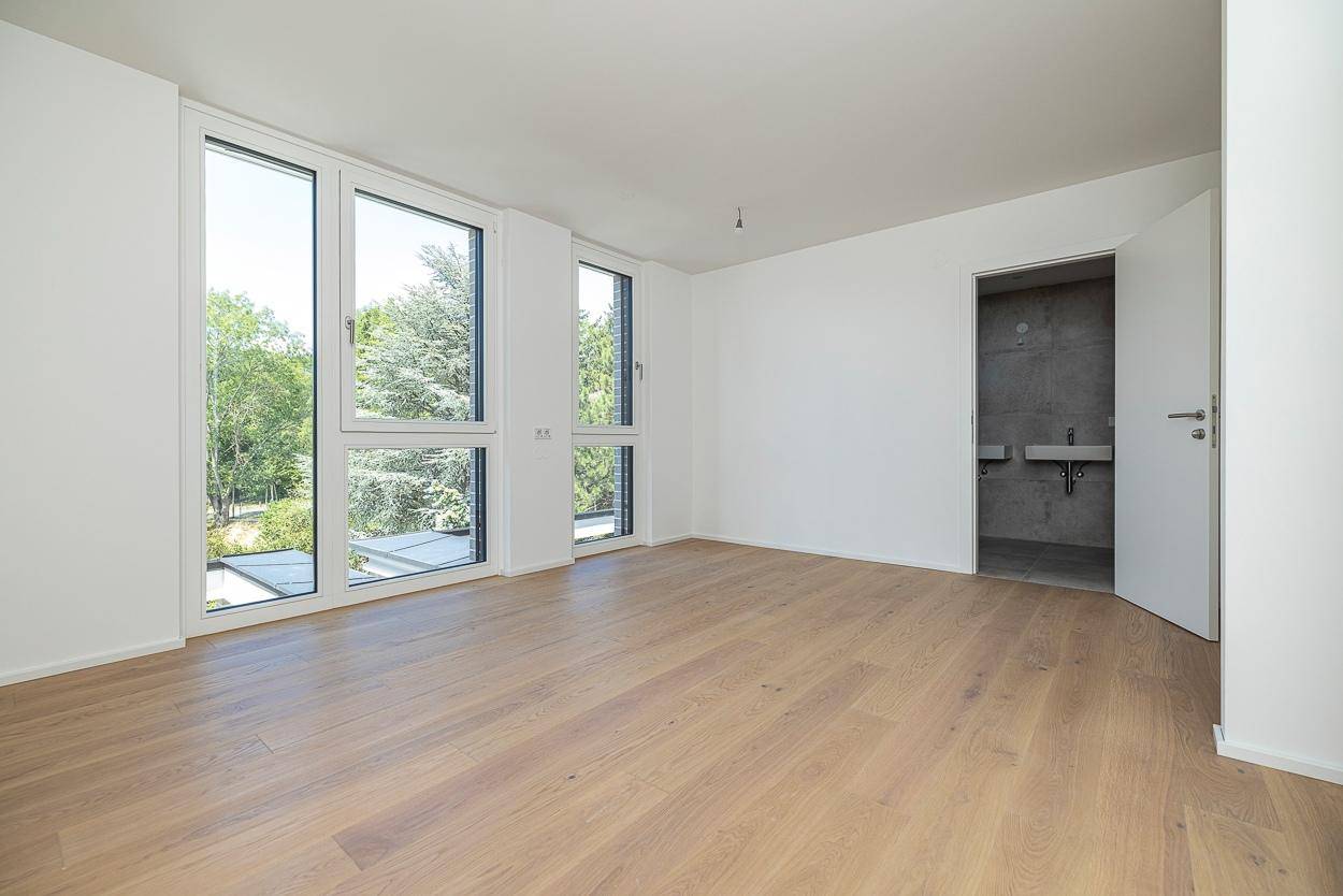Helles Schlafzimmer mit Holzboden und Zugang zu einem modernen Badezimmer.