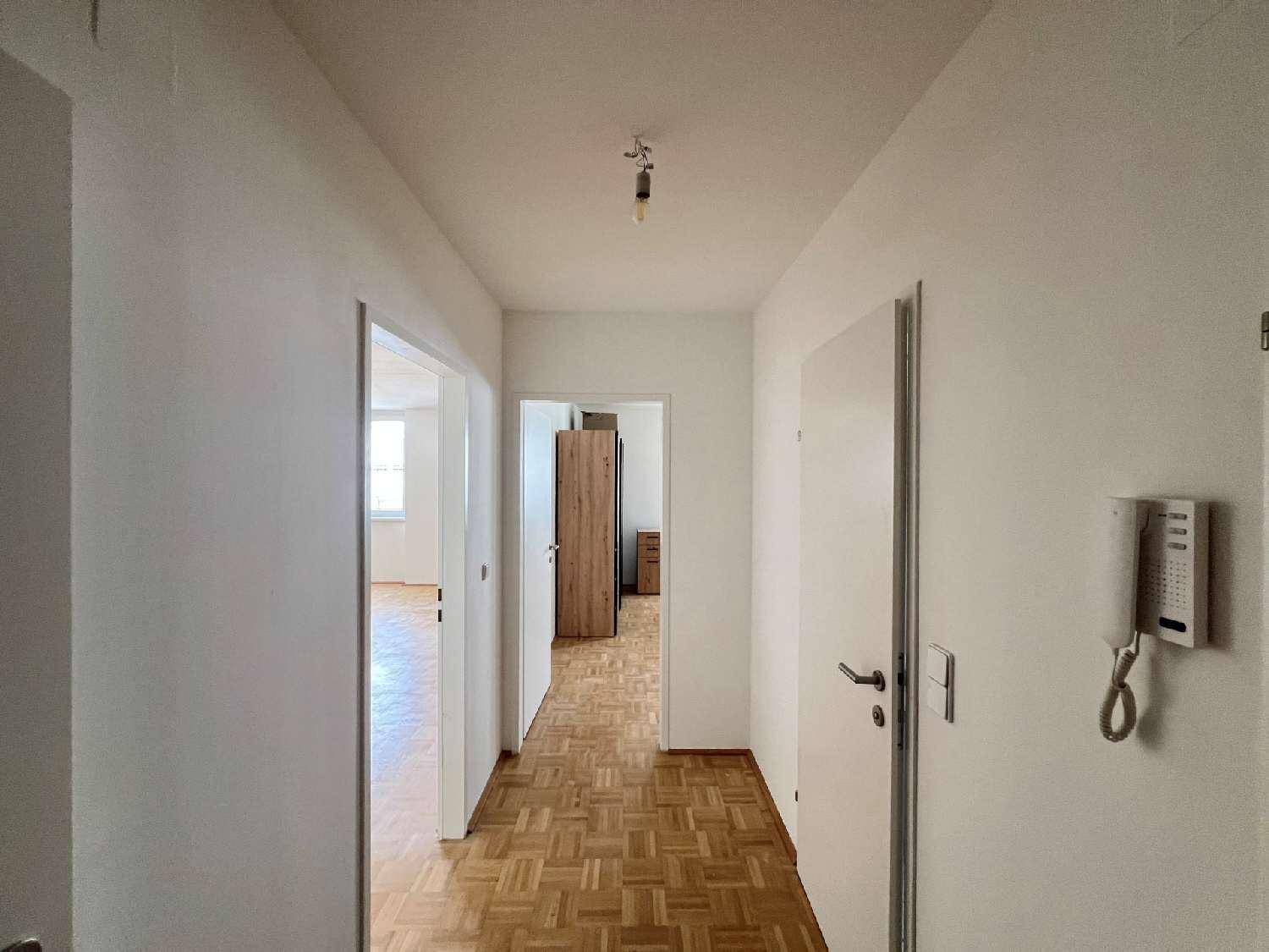Heller Flur mit Parkettboden und weißen Wänden, der zu verschiedenen Zimmern der Wohnung führt.