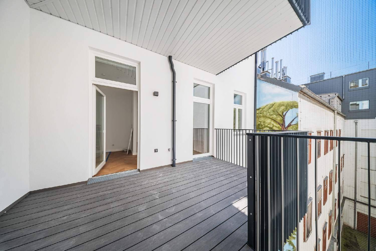 Breiter Balkon mit dunklem Dielenboden und Zugang zu mehreren Innenräumen.