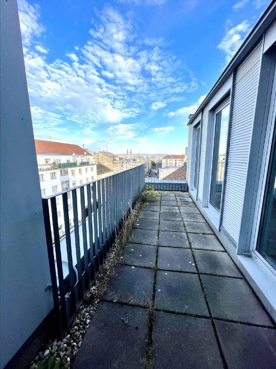 Langer Balkon mit Stadtblick und blauem Himmel, ideal für entspannte Stunden im Freien.