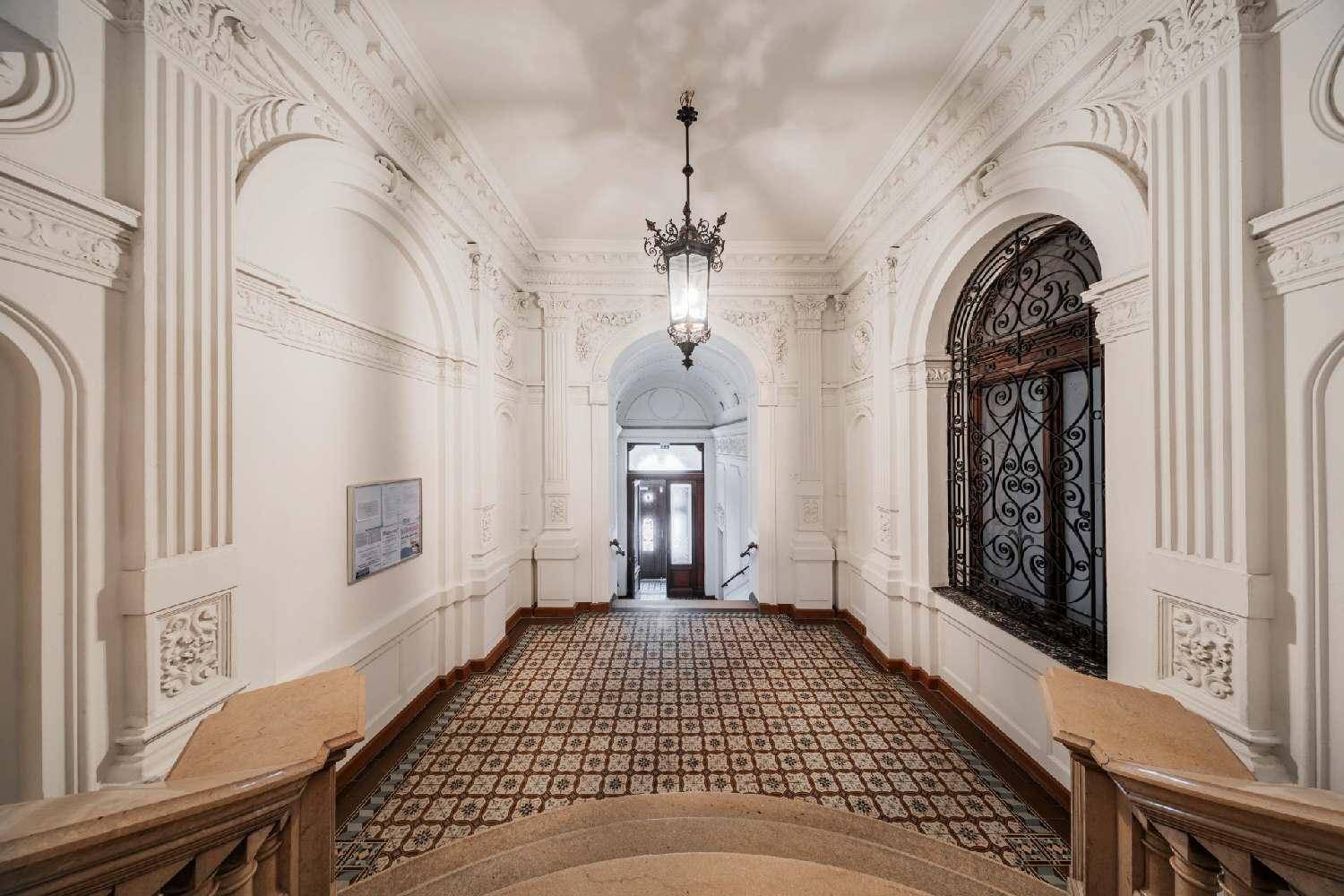 Prunkvoller Eingangsbereich mit Stuckverzierungen, historischen Fliesen und eleganter Beleuchtung.