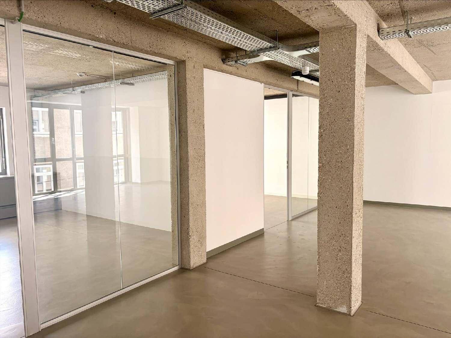 Geräumiger Büroraum mit Betonstützen, Glasabtrennungen und sichtbaren Deckeninstallationen.