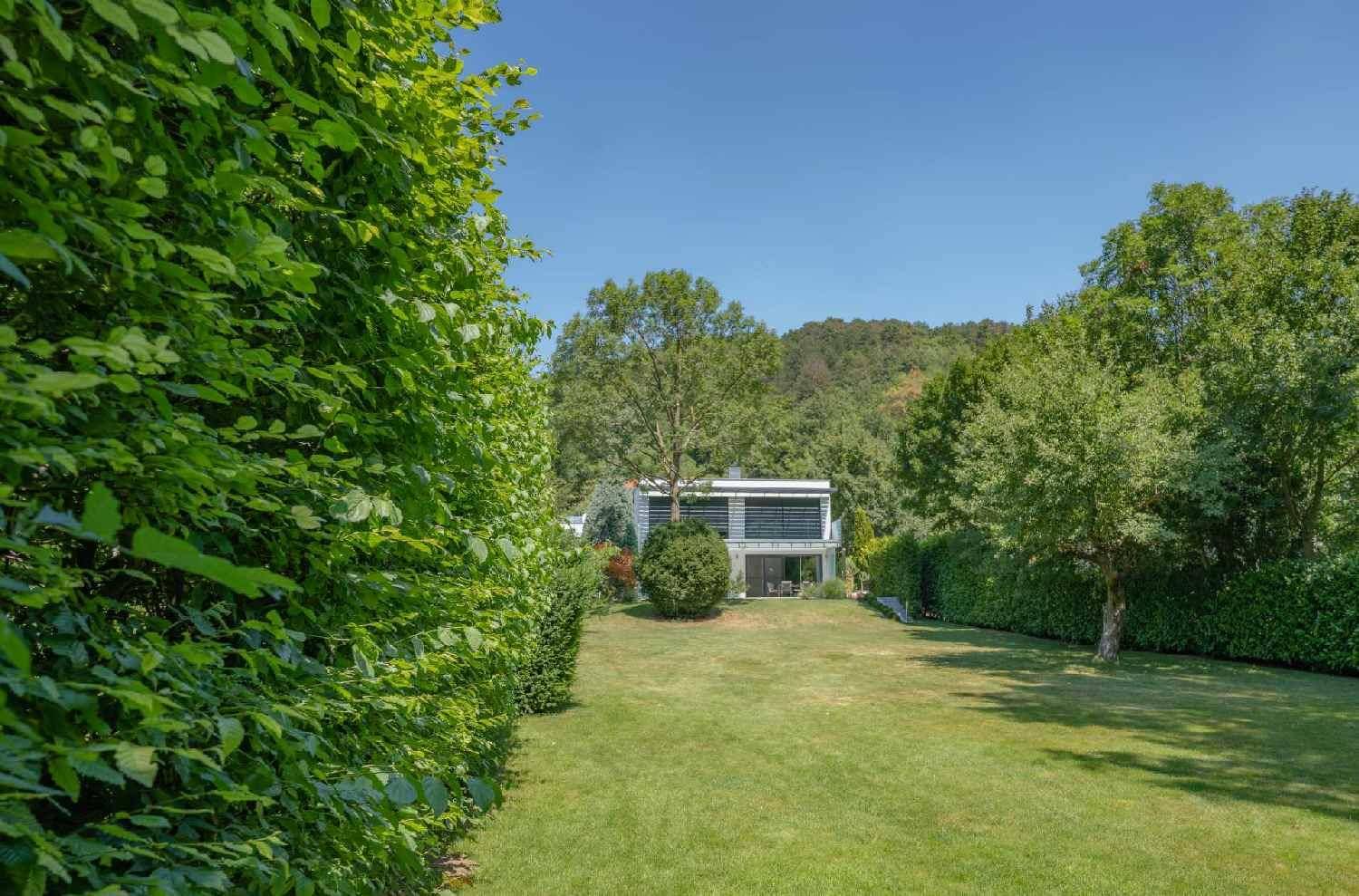 Weitläufiger Garten mit gepflegtem Rasen und Blick auf ein modernes Haus im Grünen.