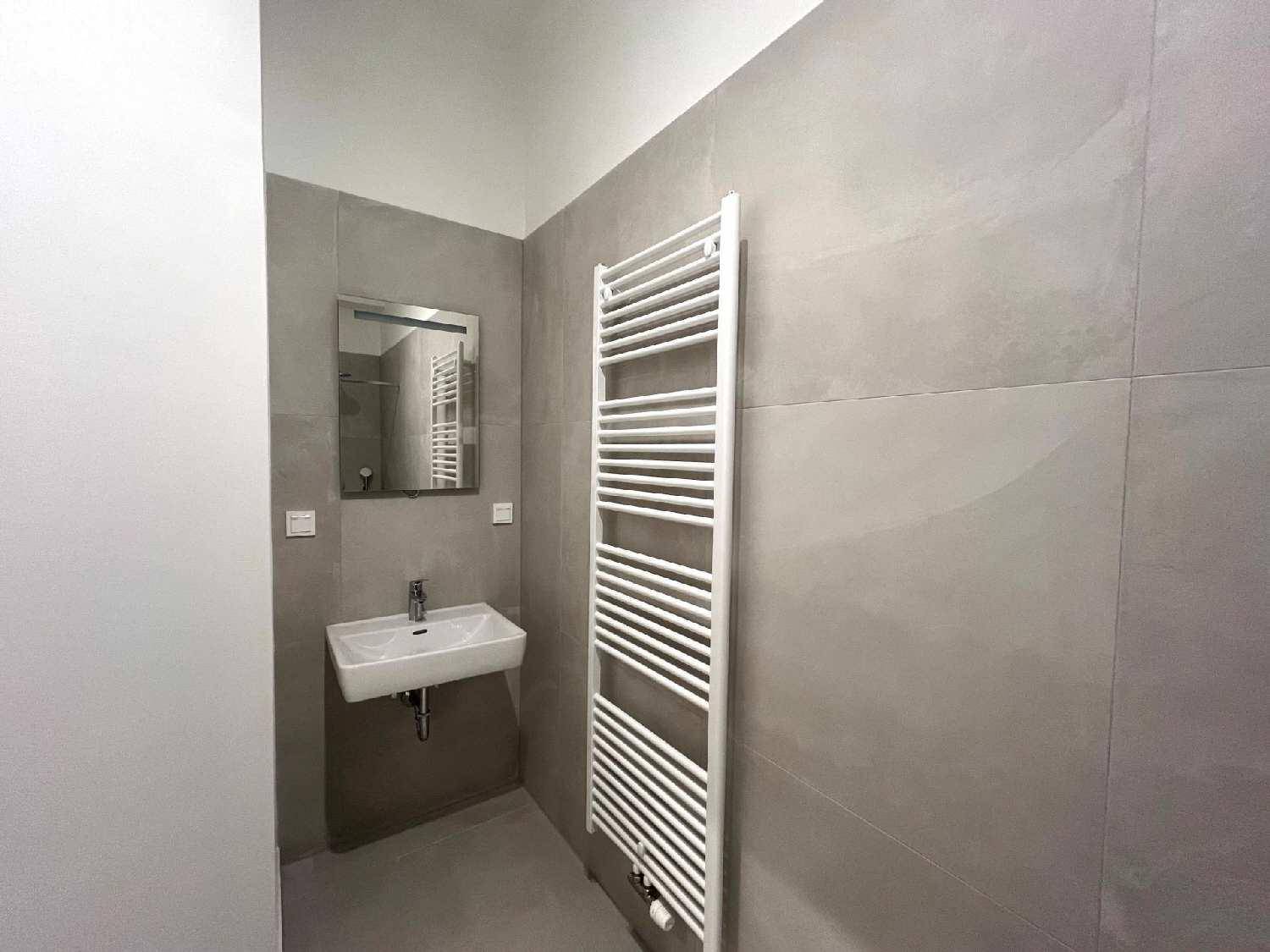 Modernes Badezimmer mit grauen Fliesen, einem Waschbecken und einem beheizten Handtuchhalter.