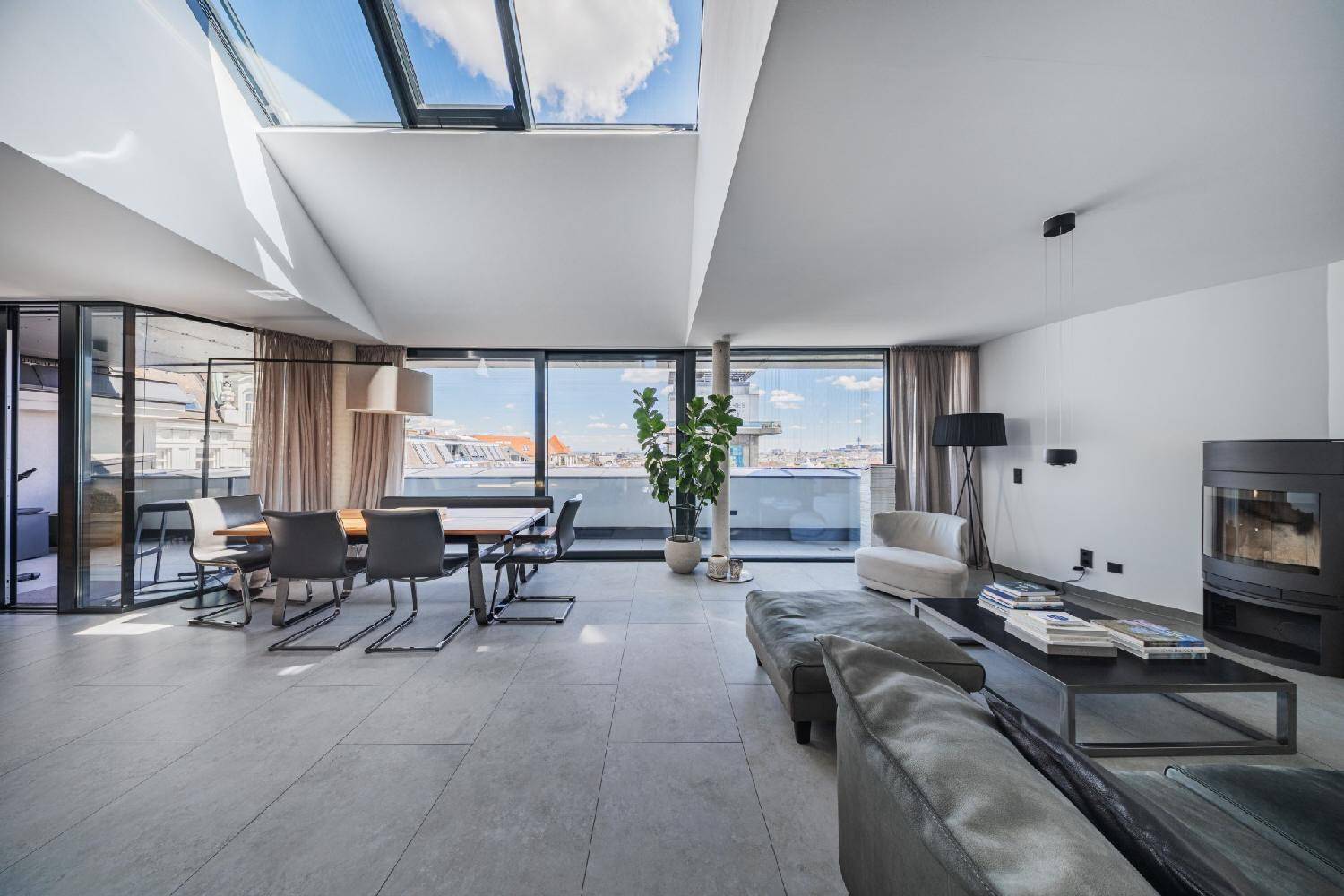 Heller Wohn- und Essbereich mit Dachfenstern, Kamin und weitem Stadtblick.