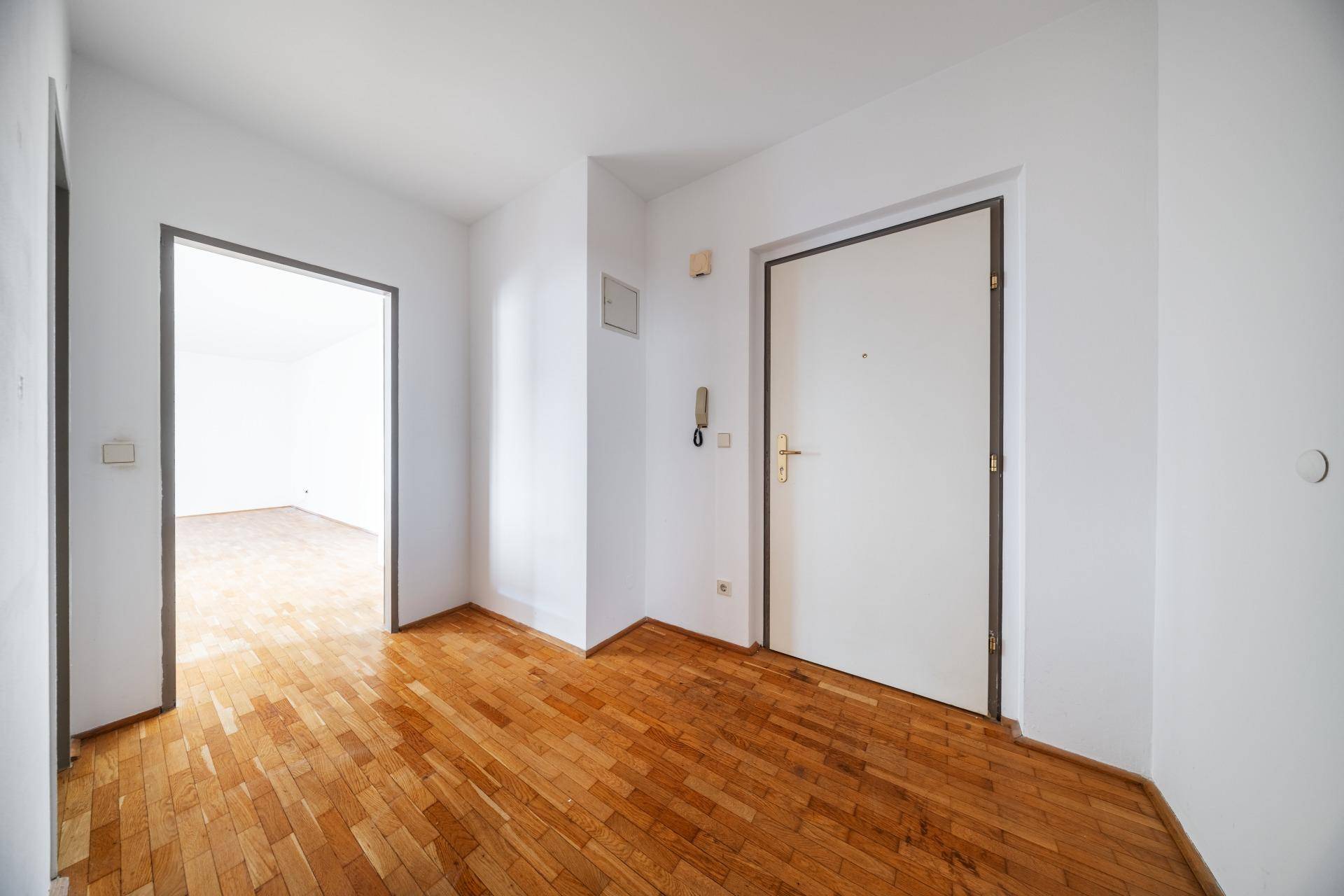 Heller Flur mit Parkettboden und zwei Türen, die zu anderen Räumen führen.