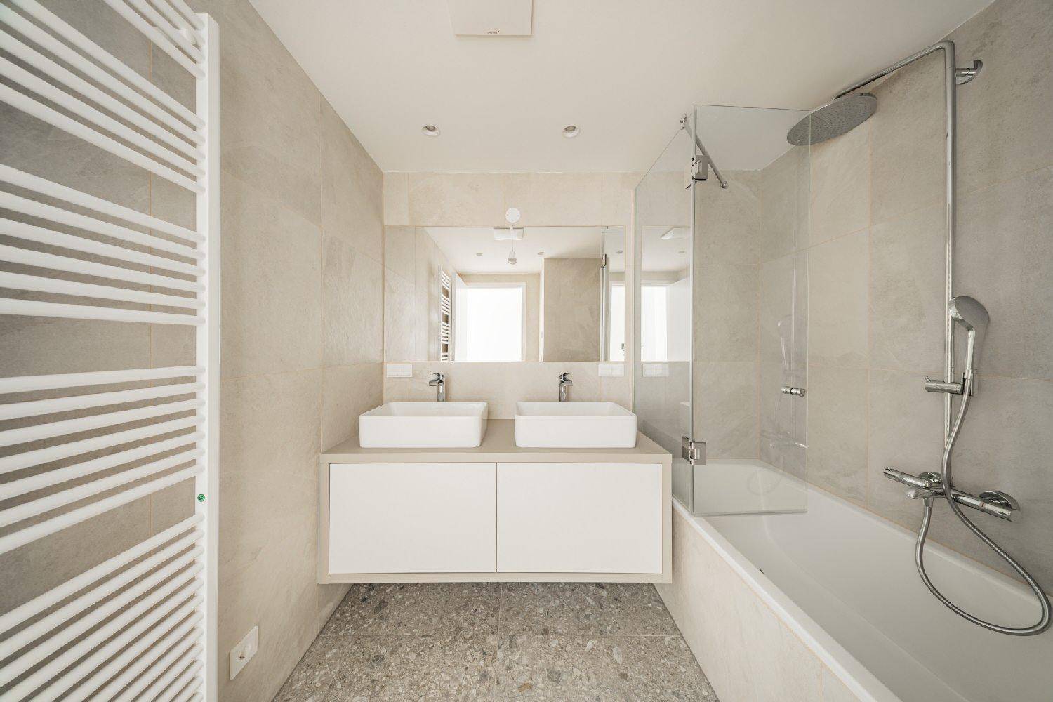 Modernes Badezimmer mit Doppelwaschbecken, Badewanne und beheiztem Handtuchhalter.