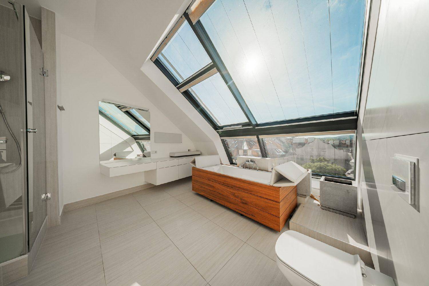 Modernes Badezimmer mit freistehender Holzbadewanne und großen Dachfenstern für viel Tageslicht.