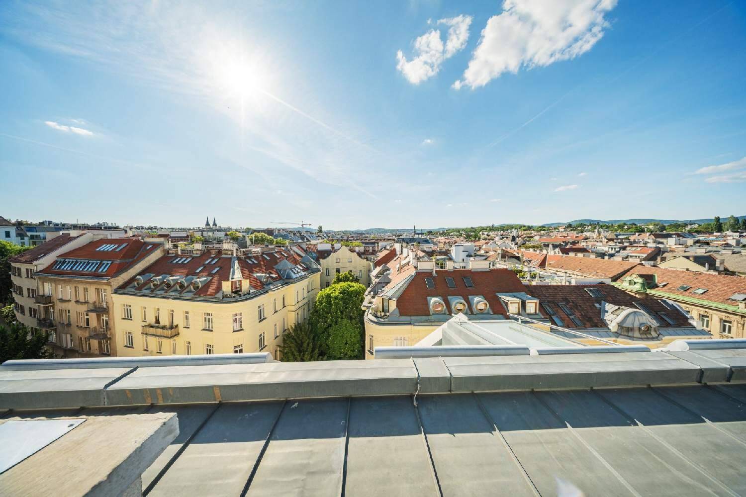 Sonniger Ausblick über die Dächer der Stadt mit historischen Gebäuden und weitem Horizont.
