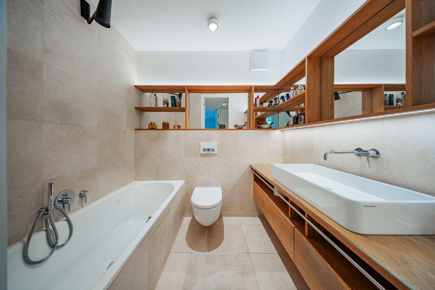 Modernes Badezimmer mit Badewanne, wandhängendem WC und Doppelwaschbecken.