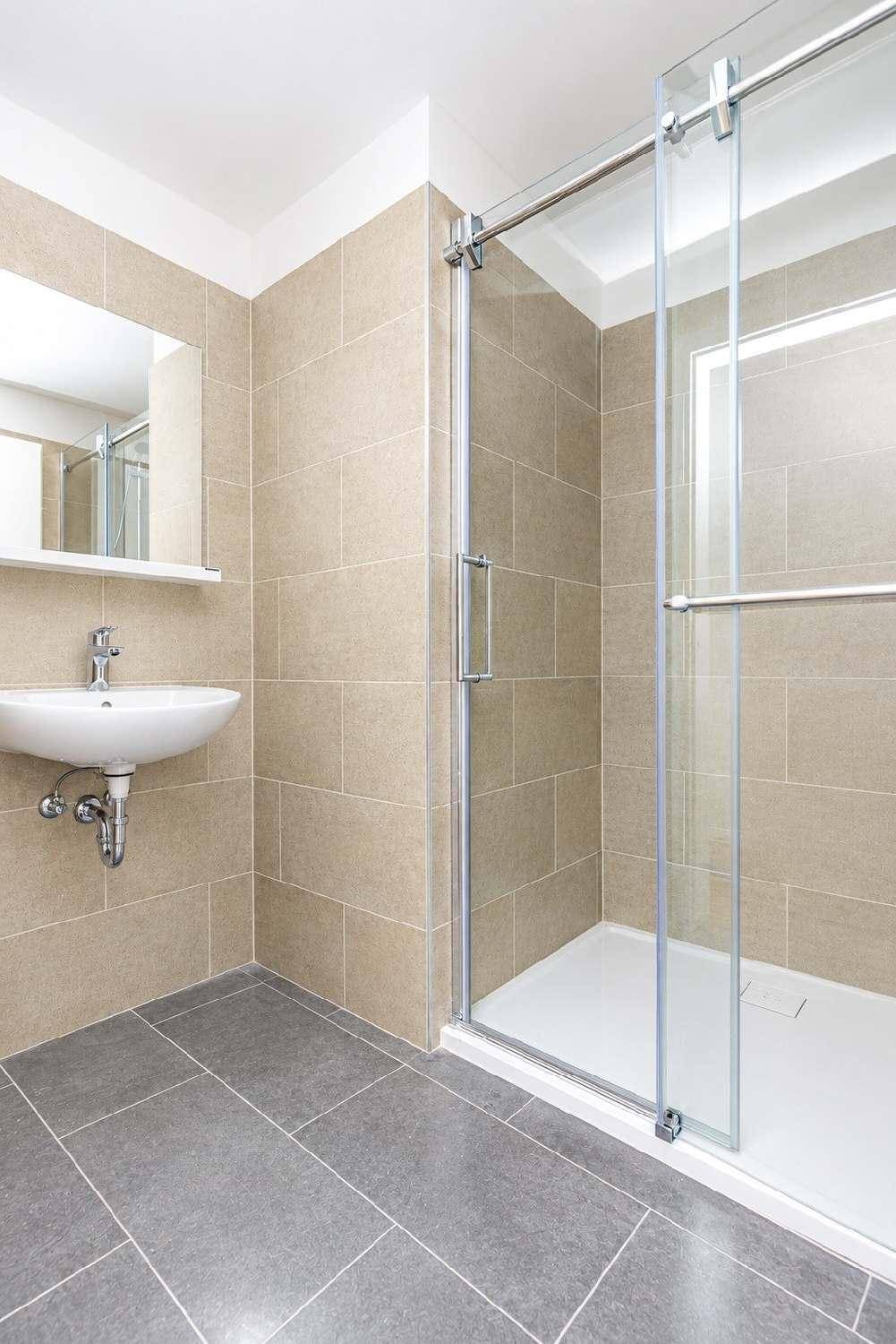 Modernes Badezimmer mit beigefarbenen Wandfliesen, begehbarer Dusche und Einzelwaschbecken.