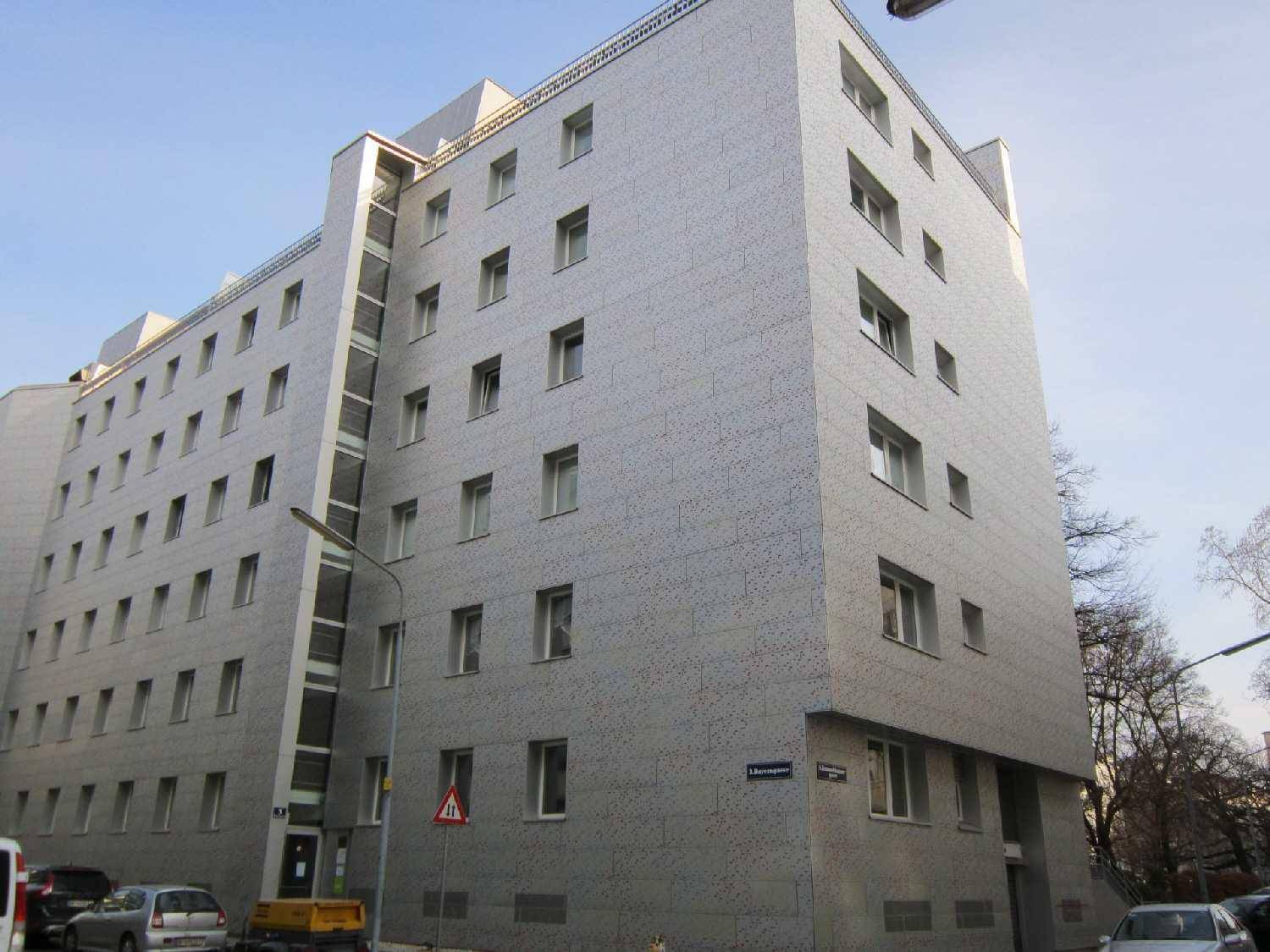 Modernes Mehrfamilienhaus mit heller Fassade und vielen Fenstern in städtischer Umgebung.