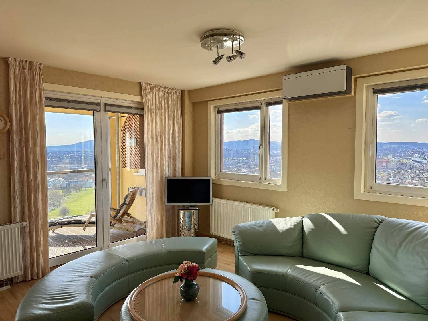 Helles Wohnzimmer mit bequemer Ledercouch, Klimaanlage und Zugang zum Balkon mit Aussicht.