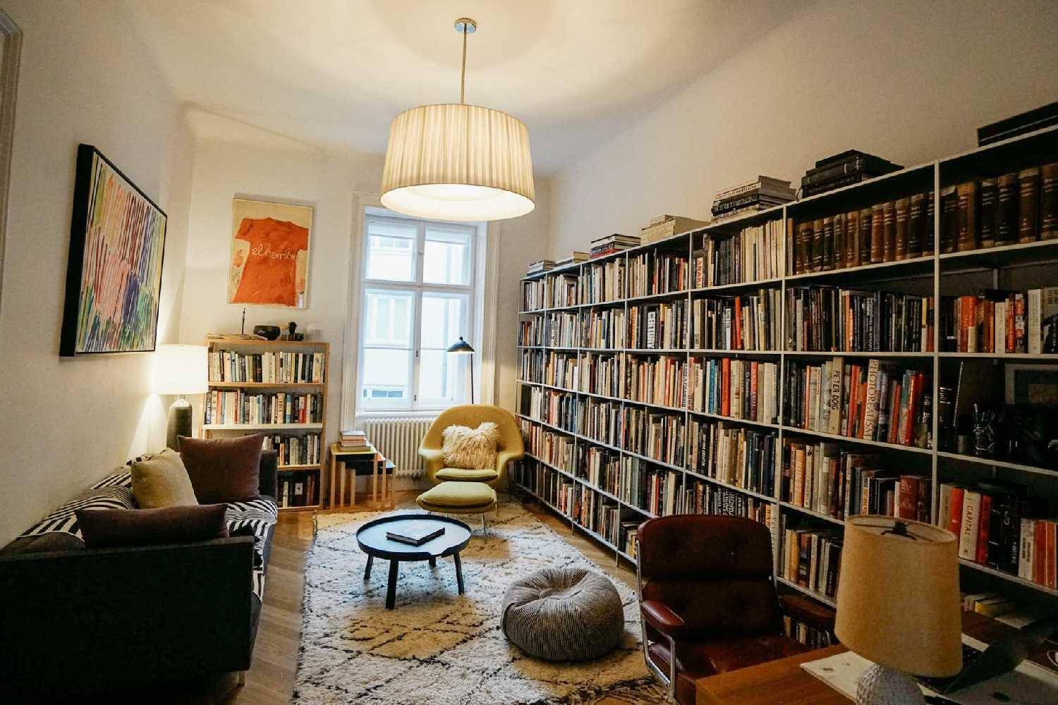 Gemütliche Bibliothek mit raumhohen Bücherregalen, bequemen Sesseln und Teppichboden.