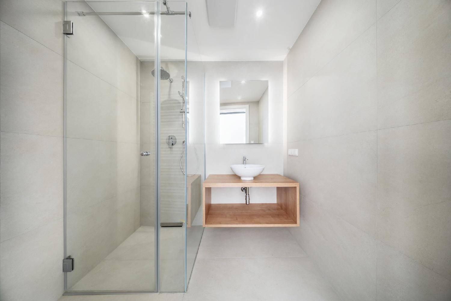 Elegantes Badezimmer mit begehbarer Dusche, modernem Waschtisch und hellen Fliesen.