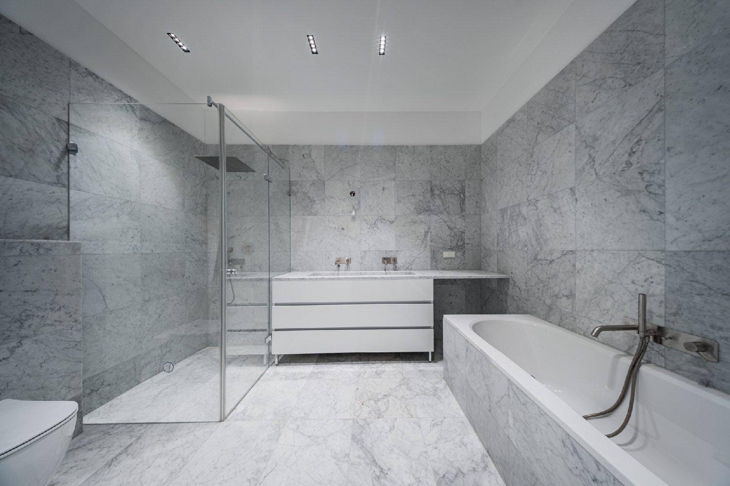 Luxuriöses Badezimmer mit Marmorfliesen, großer begehbarer Dusche und moderner Badewanne.