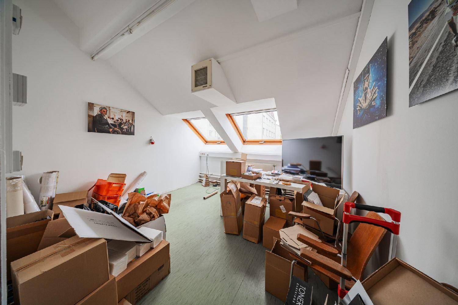 Dachgeschossraum mit vielen Umzugskartons, schrägen Decken und Dachfenstern, derzeit als Lager genutzt.