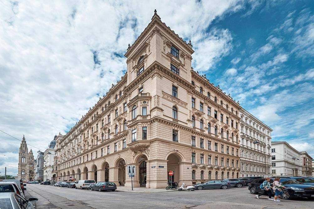 Historisches Eckgebäude mit beeindruckender Architektur, vielen Fenstern und einer belebten Straße davor.