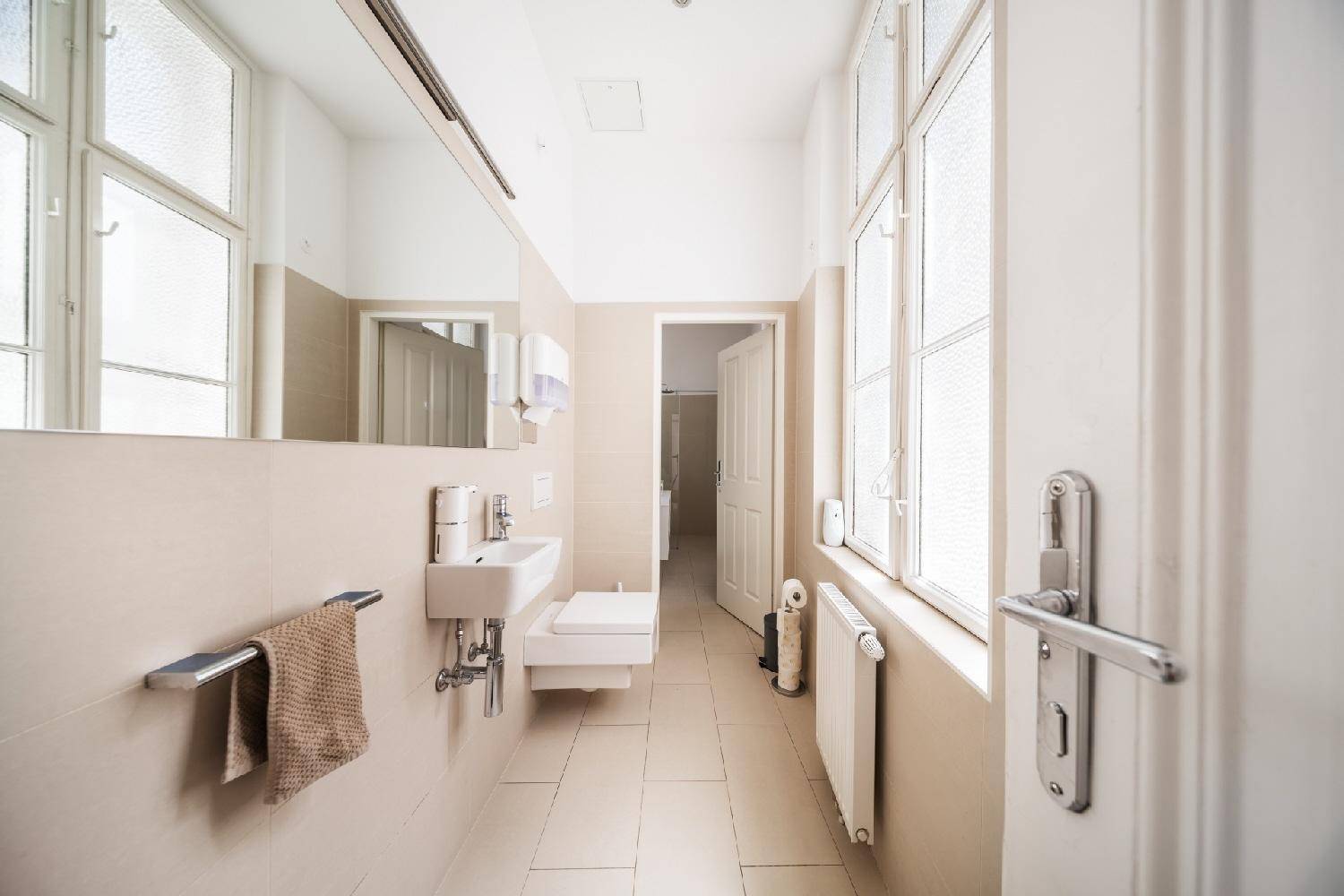Helles Badezimmer mit Waschbecken, Toilette und Fenster für natürliche Belüftung.