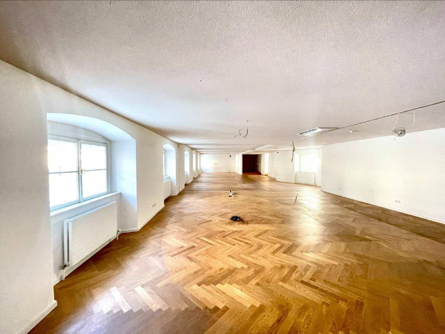 Geräumiger, heller Büroraum mit Fischgrätparkett und einer Reihe von Fenstern.