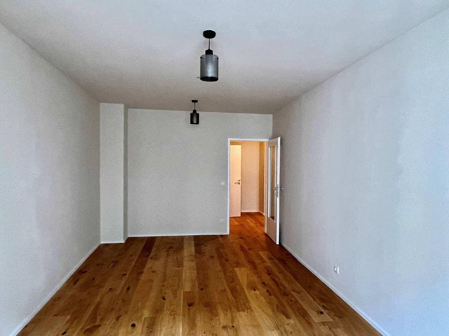 Geräumiges Zimmer mit hellem Holzparkett und Zugang zu weiteren Räumen.