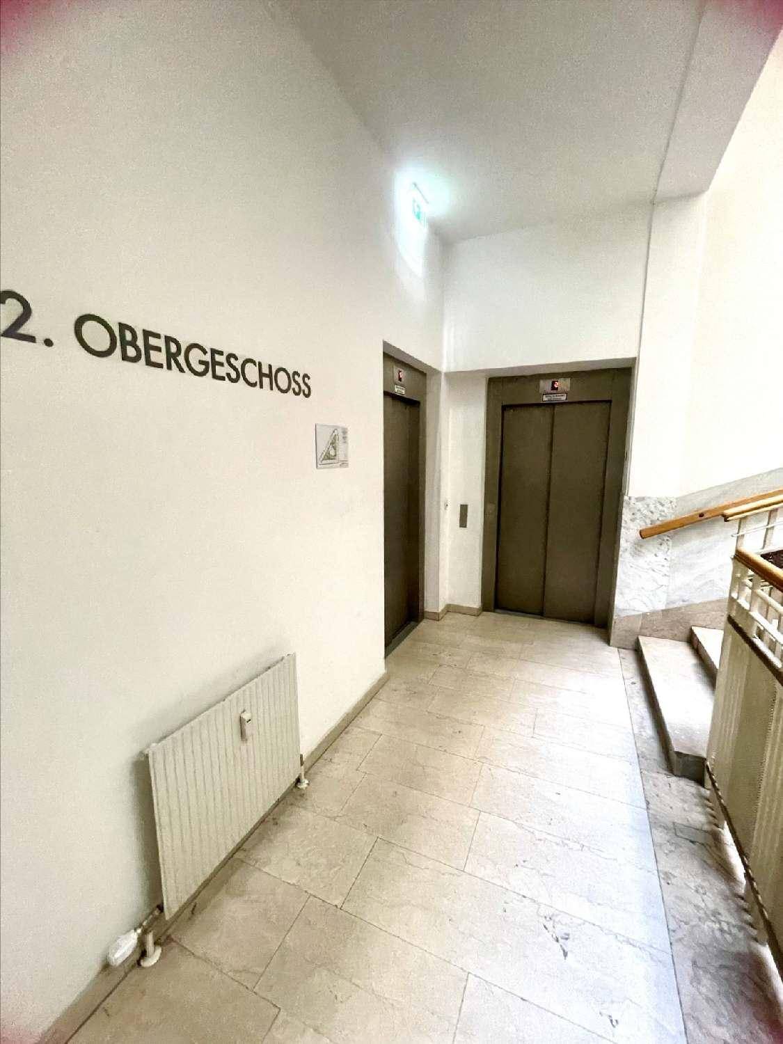 Flur im zweiten Obergeschoss mit zwei Aufzügen, Fliesenboden und angrenzendem Treppenhaus.