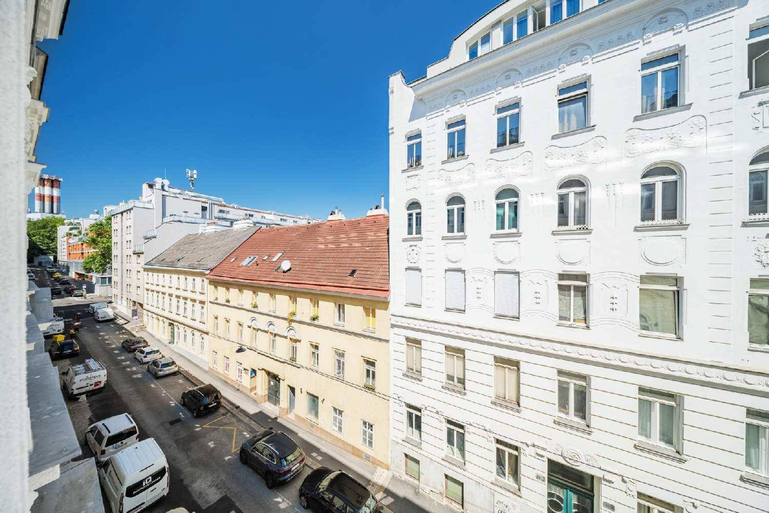 Blick von oben auf eine belebte Stadtstraße mit parkenden Autos und historischen Gebäudefassaden.