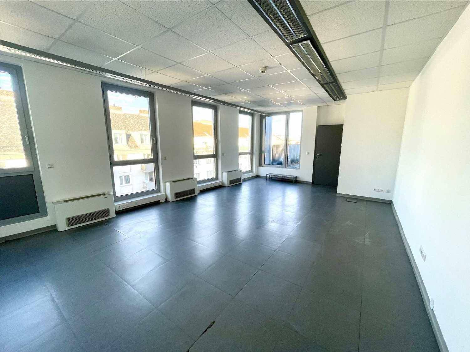 Großer, heller Büroraum mit vielen Fenstern und grauen Bodenfliesen, ideal für eine offene Bürogestaltung.