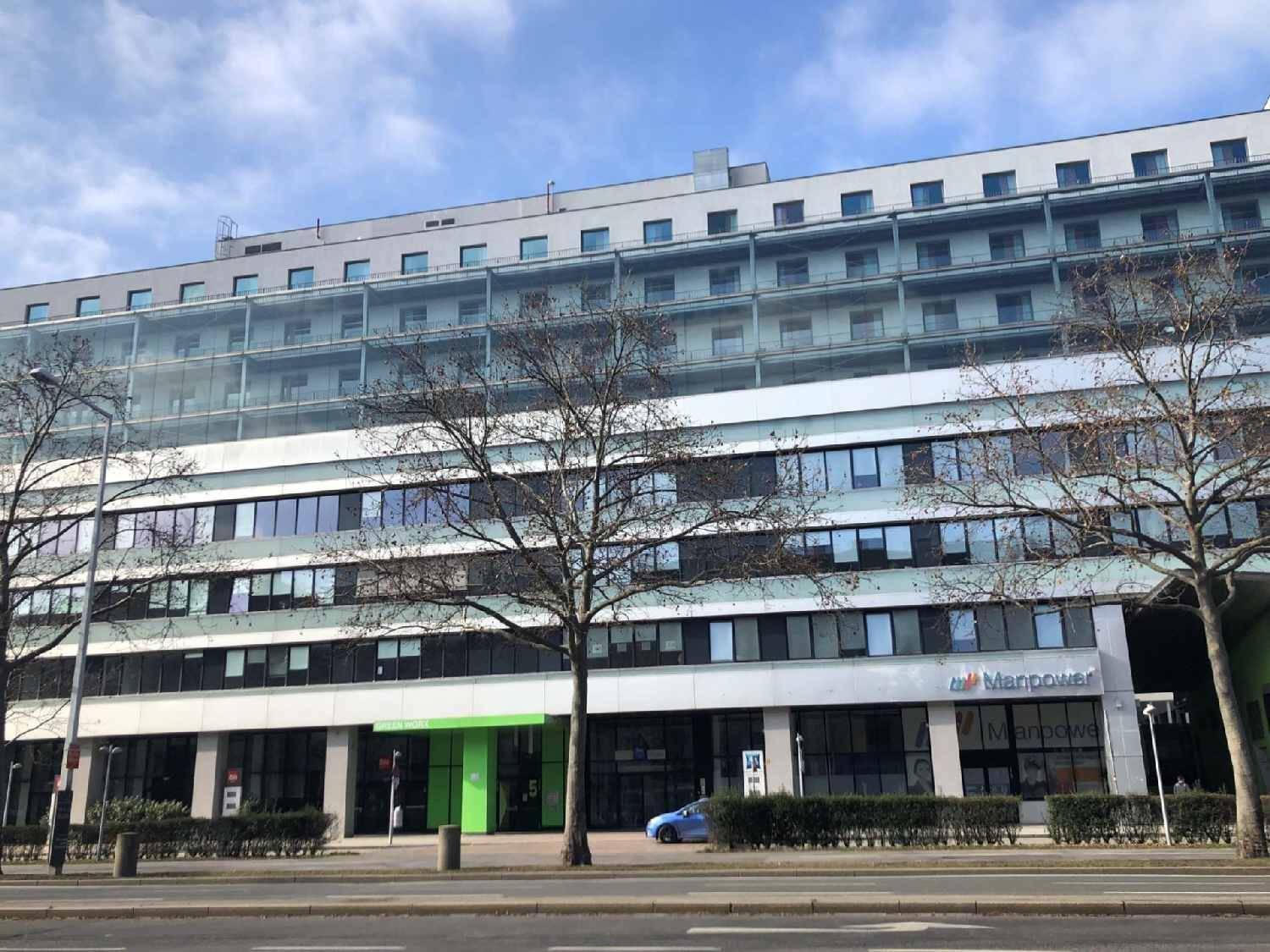 Ansicht eines großen Geschäftsgebäudes mit vielen Fenstern und einer modernen Fassade unter blauem Himmel.