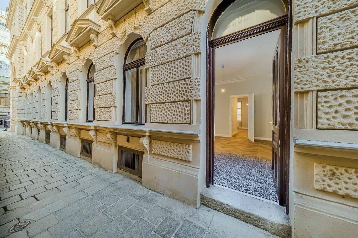 Historische Fassade eines Gebäudes mit großen Fenstern und einem offenen Eingang, der den Blick ins Innere freigibt.