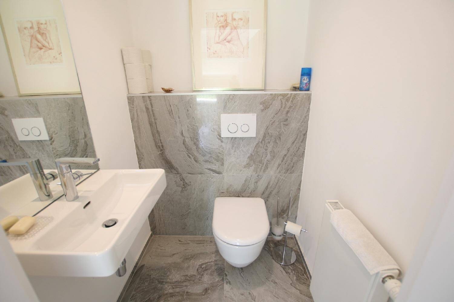 Modernes Gäste-WC mit Wand-WC, Einzelwaschbecken und eleganten Marmorfliesen.