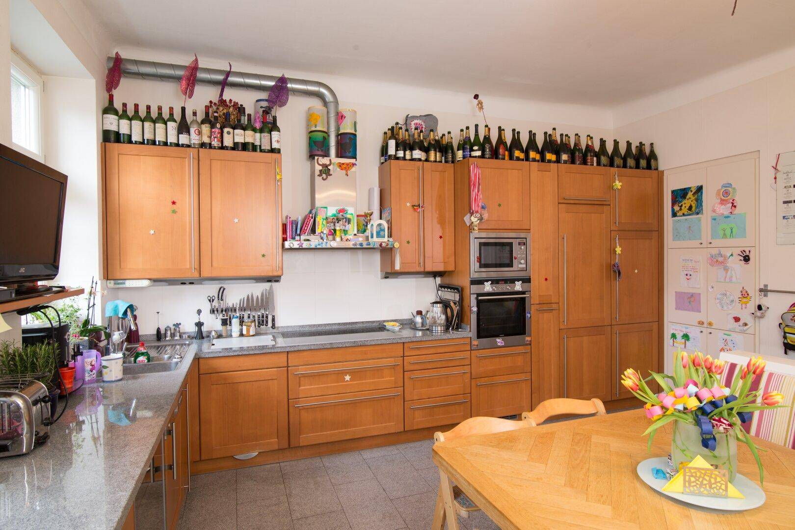 Funktionale Küche mit Holzschränken, integrierten Geräten und einem Essbereich für die Familie.