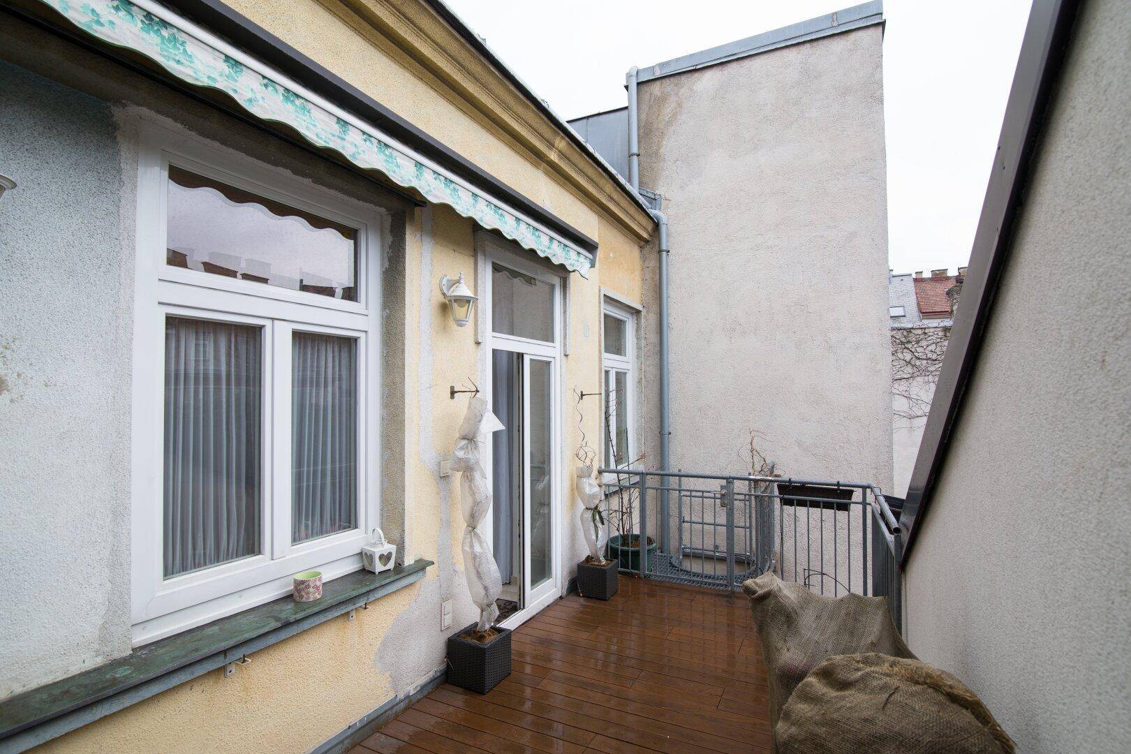 Kleiner Balkon mit Holzboden und Blick auf die umliegenden Gebäude.