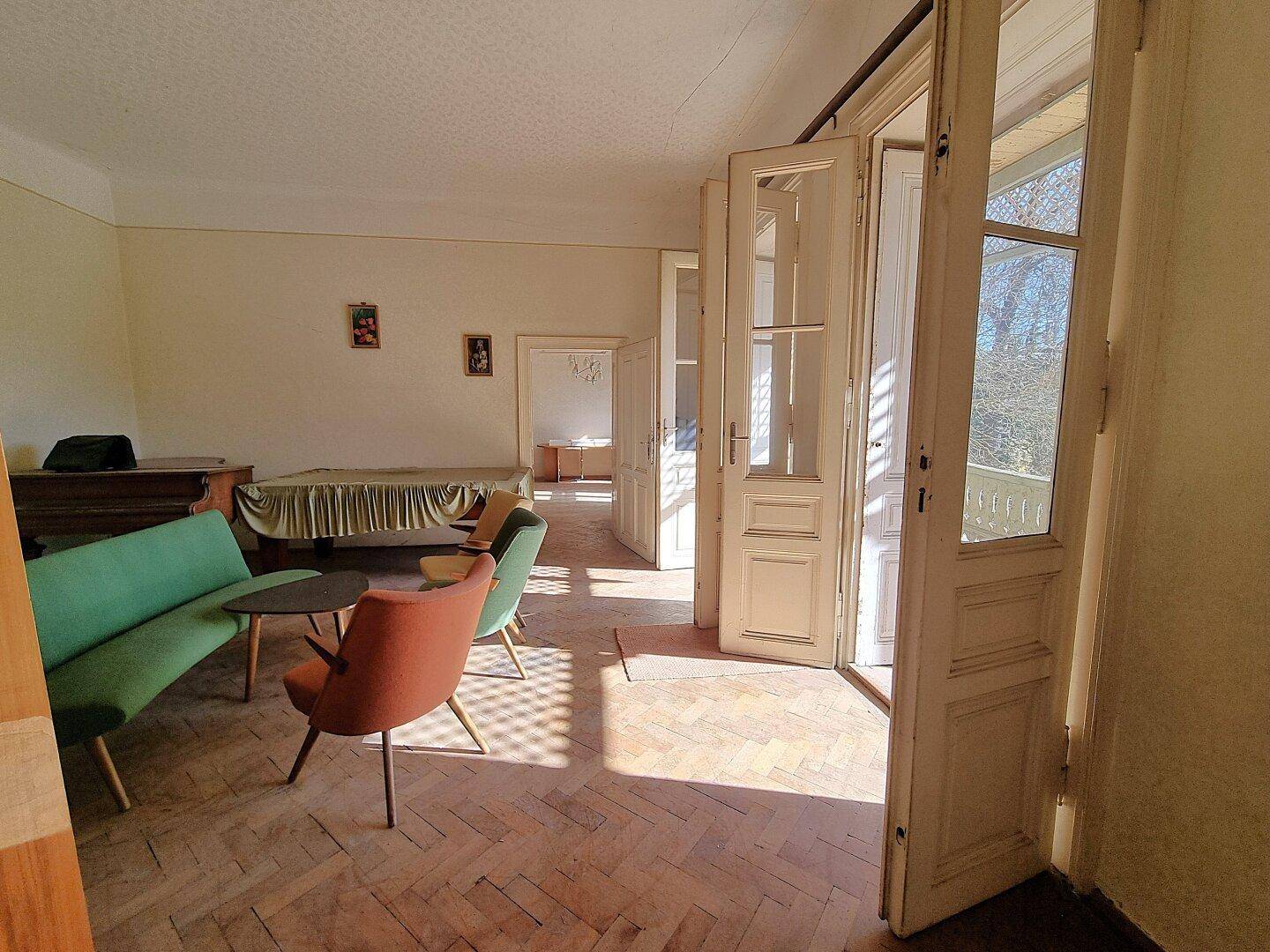 Helles Wohnzimmer mit Fischgrätparkett und Zugang zum Balkon, teilweise möbliert.