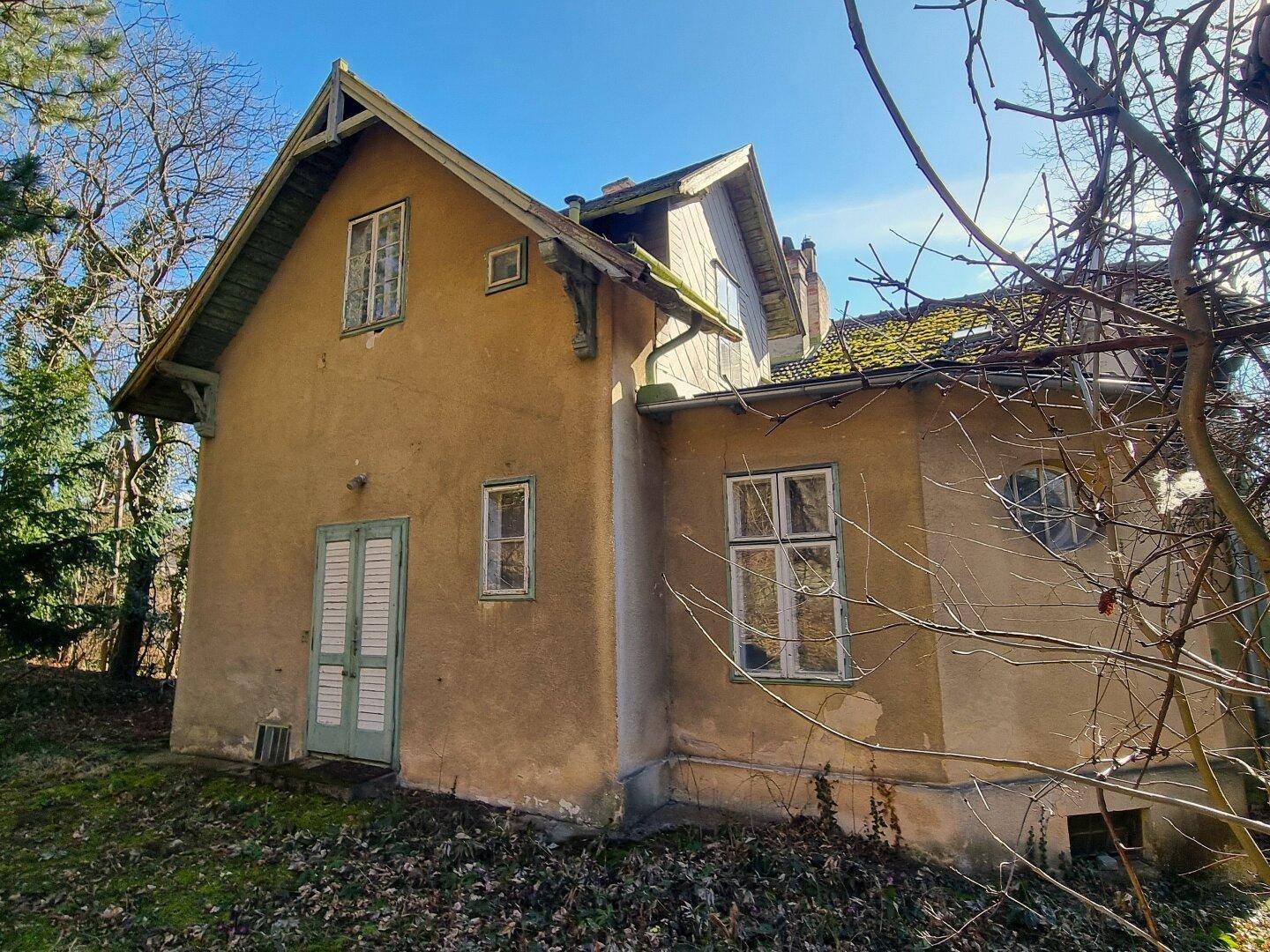 Seitenansicht des historischen Gebäudes mit gelber Fassade und grünen Fensterläden.