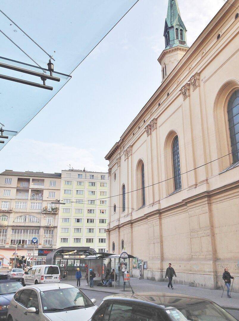 Historische Kirche und belebte Straße im Stadtzentrum, umgeben von urbaner Architektur.