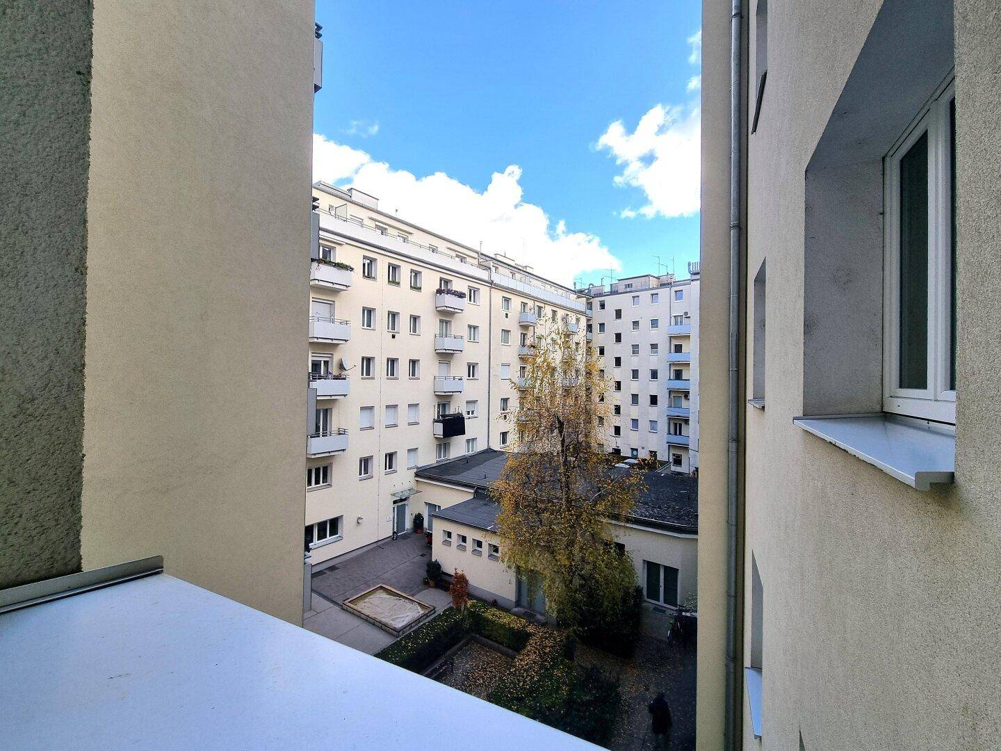 Blick in den ruhigen Innenhof mit Bäumen und Grünflächen, umgeben von Wohngebäuden.