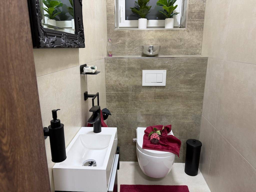 Kleines Gäste-WC mit modernem Waschbecken, Toilette und Fenster für Belüftung.