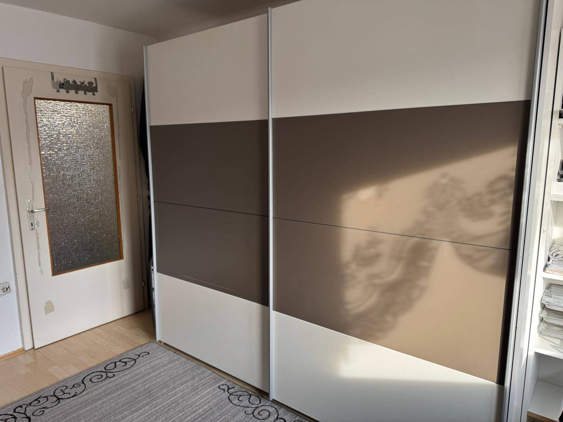 Kleiderschrank mit Schiebetüren in einem Dachgeschoss-Schlafzimmer neben einer Tür.