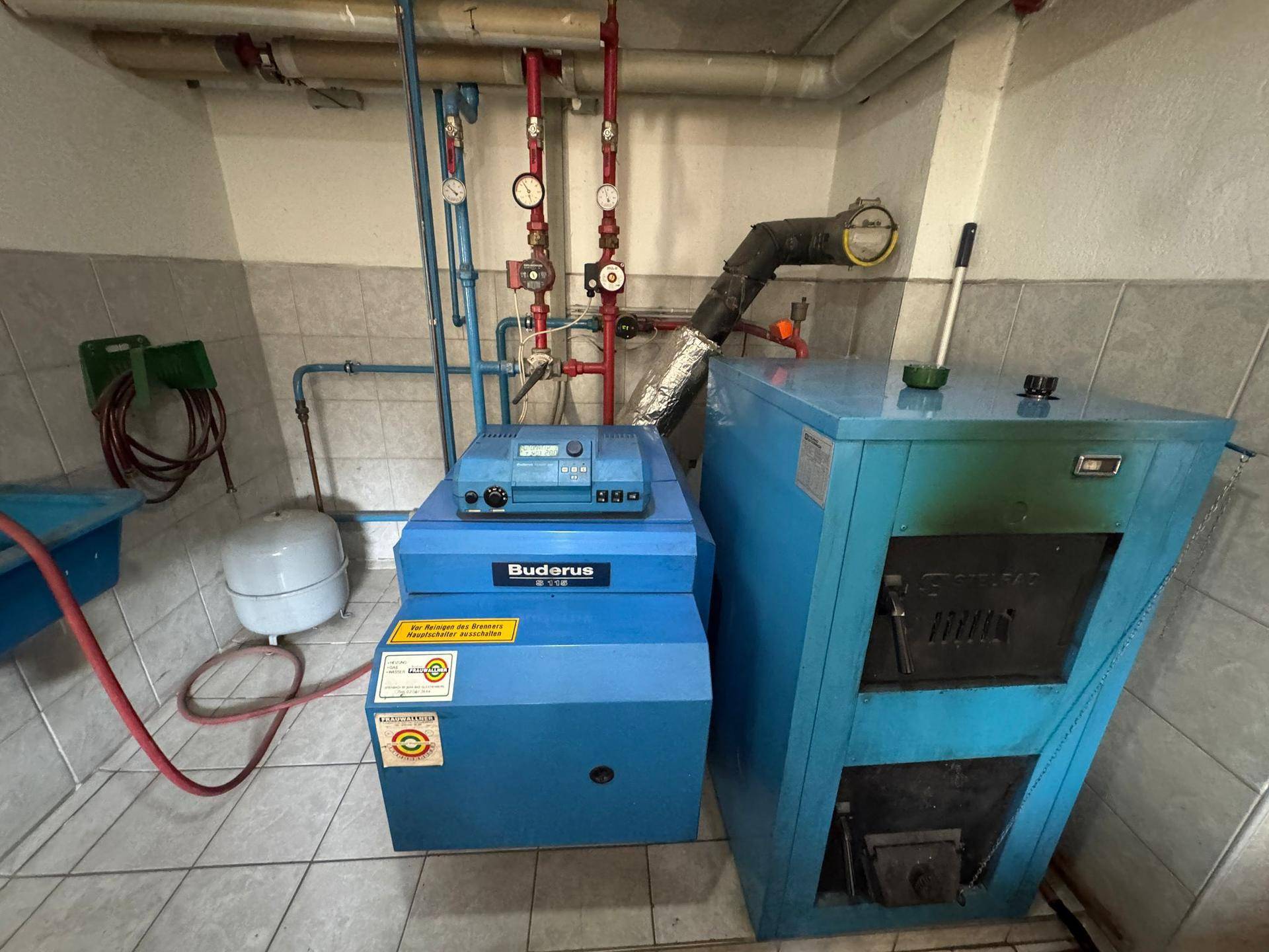 Heizungsraum im Keller mit einem Buderus-Heizkessel und zugehörigen Installationen.